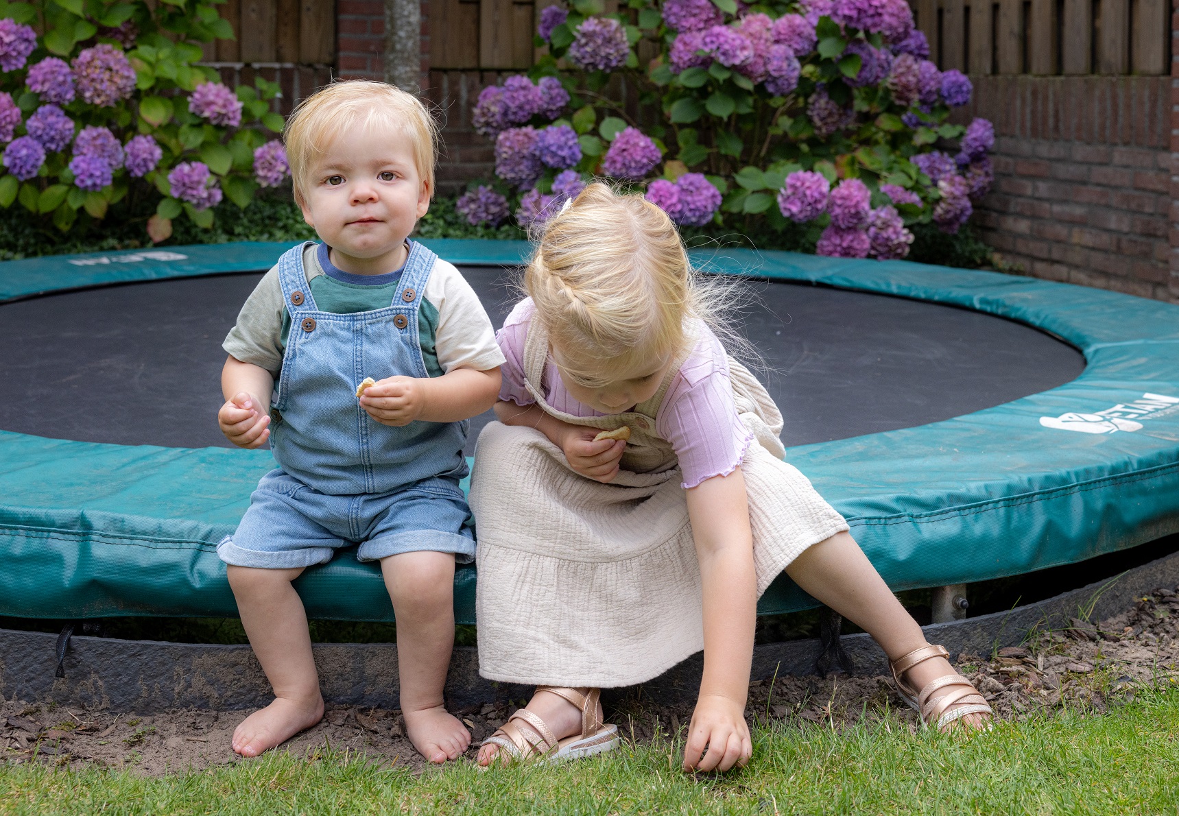 jongen en meisje zitten op de rand van een trampoline