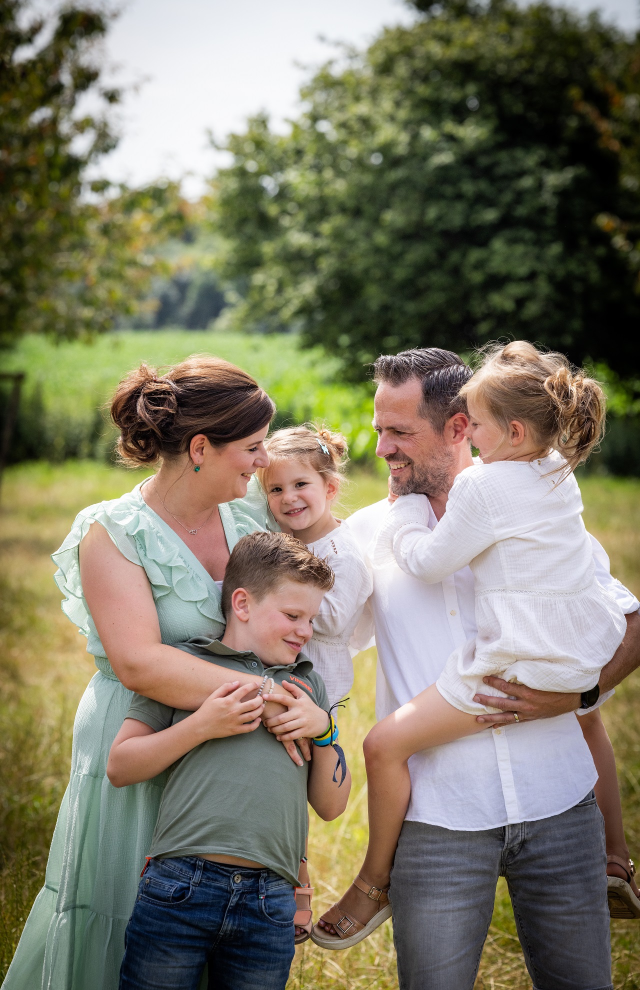 vrouw en man met hun drie kinderen buiten in het groen