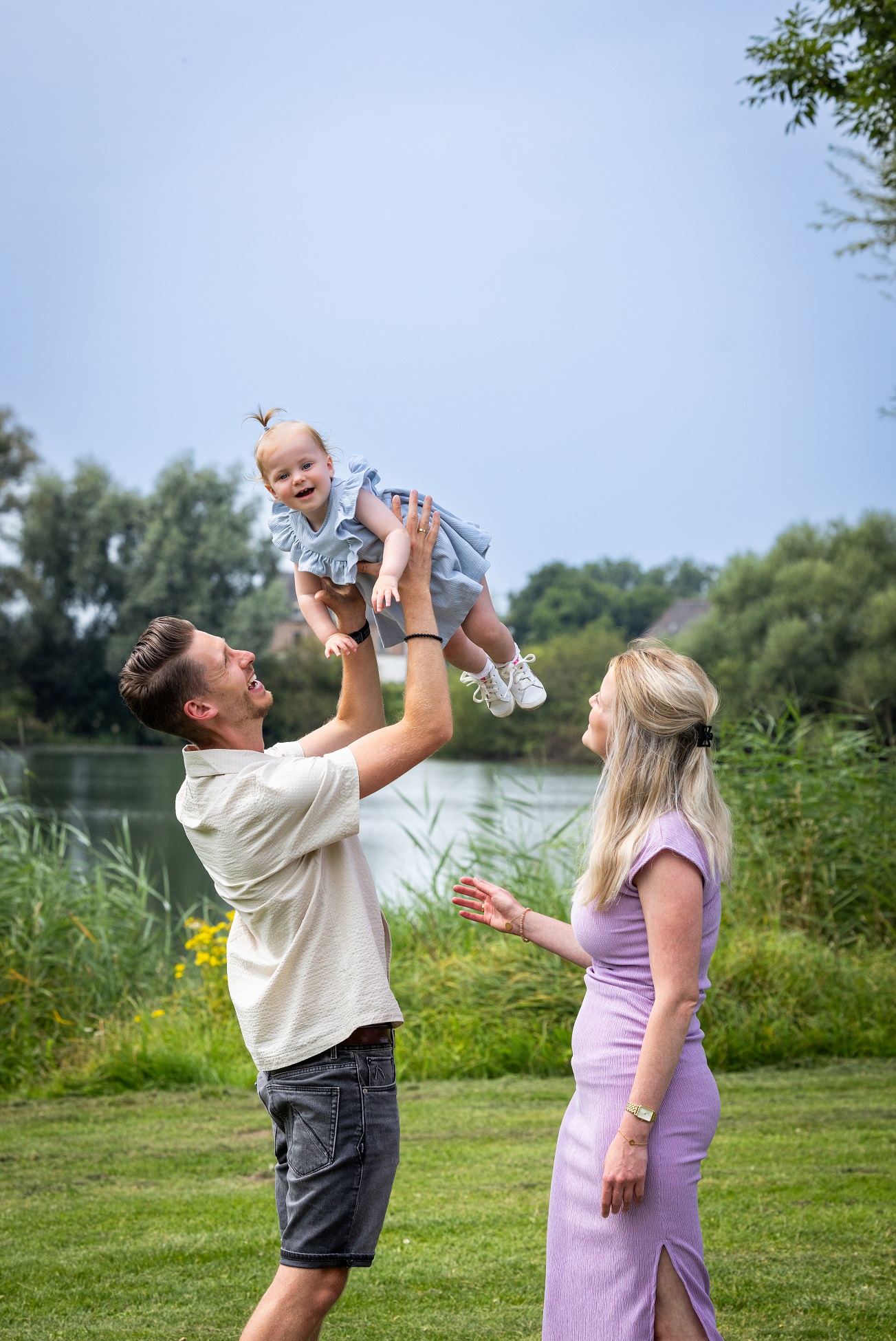 jonge man en vrouw tillen hun dochter hoog in de lucht