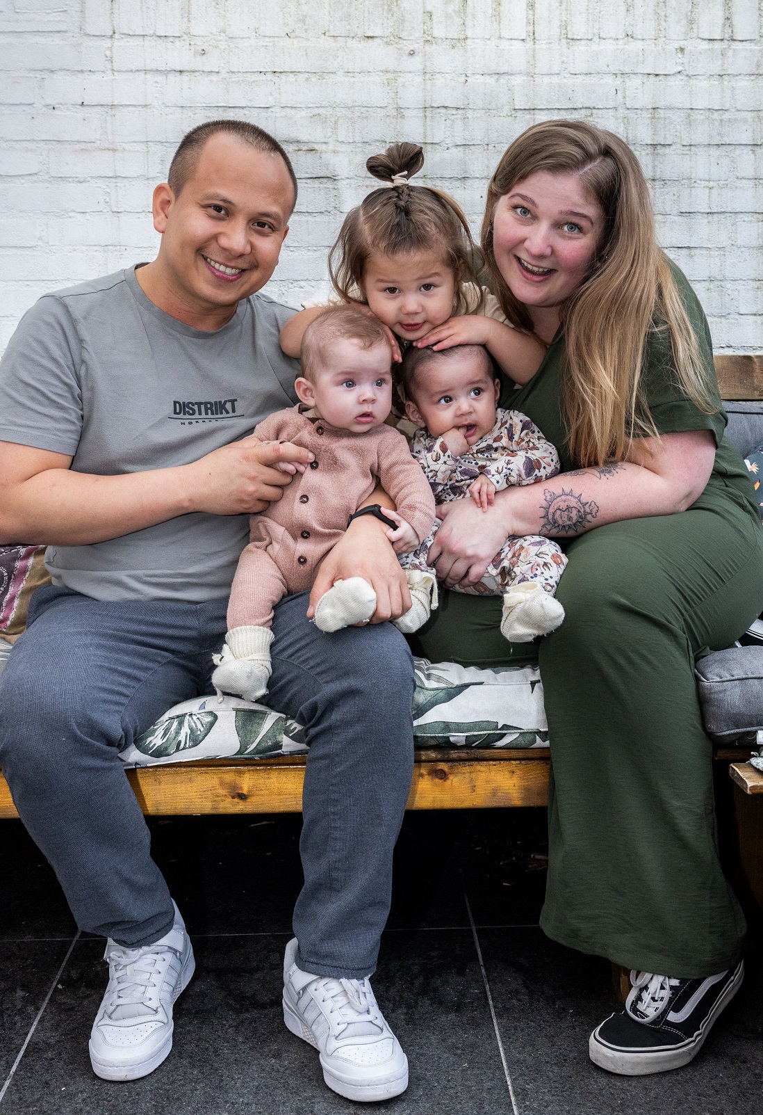 man en vrouw met hun drie kinderen op de bank