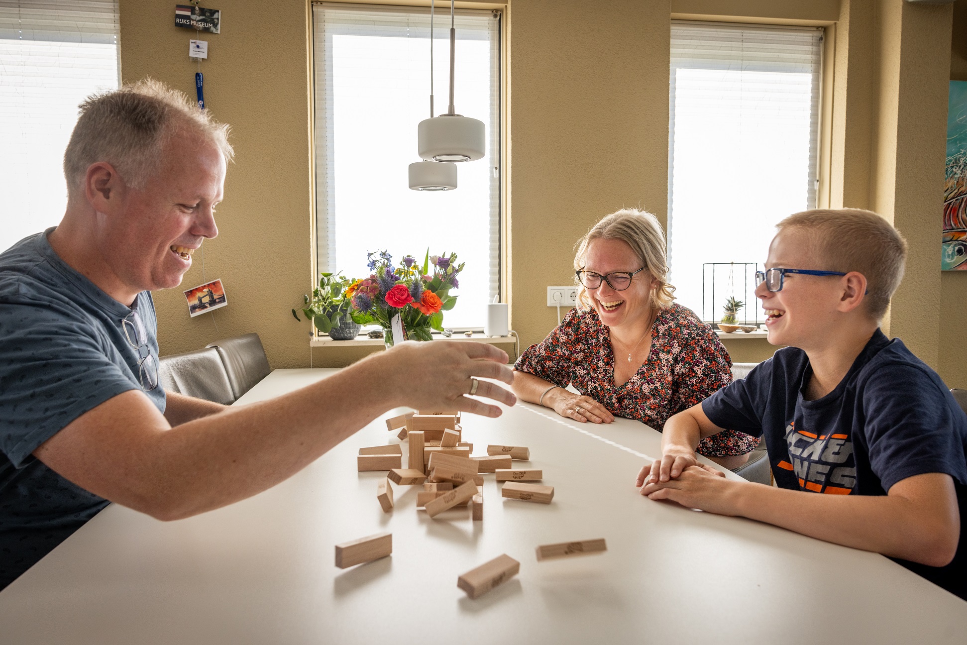 Man en vrouwen spelen met hun zoon een spel aan de eetkamertafel