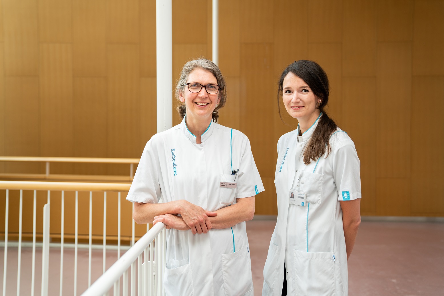 Twee neurologen van Radboudumc staan samen bij een reling in de gang van het ziekenhuis