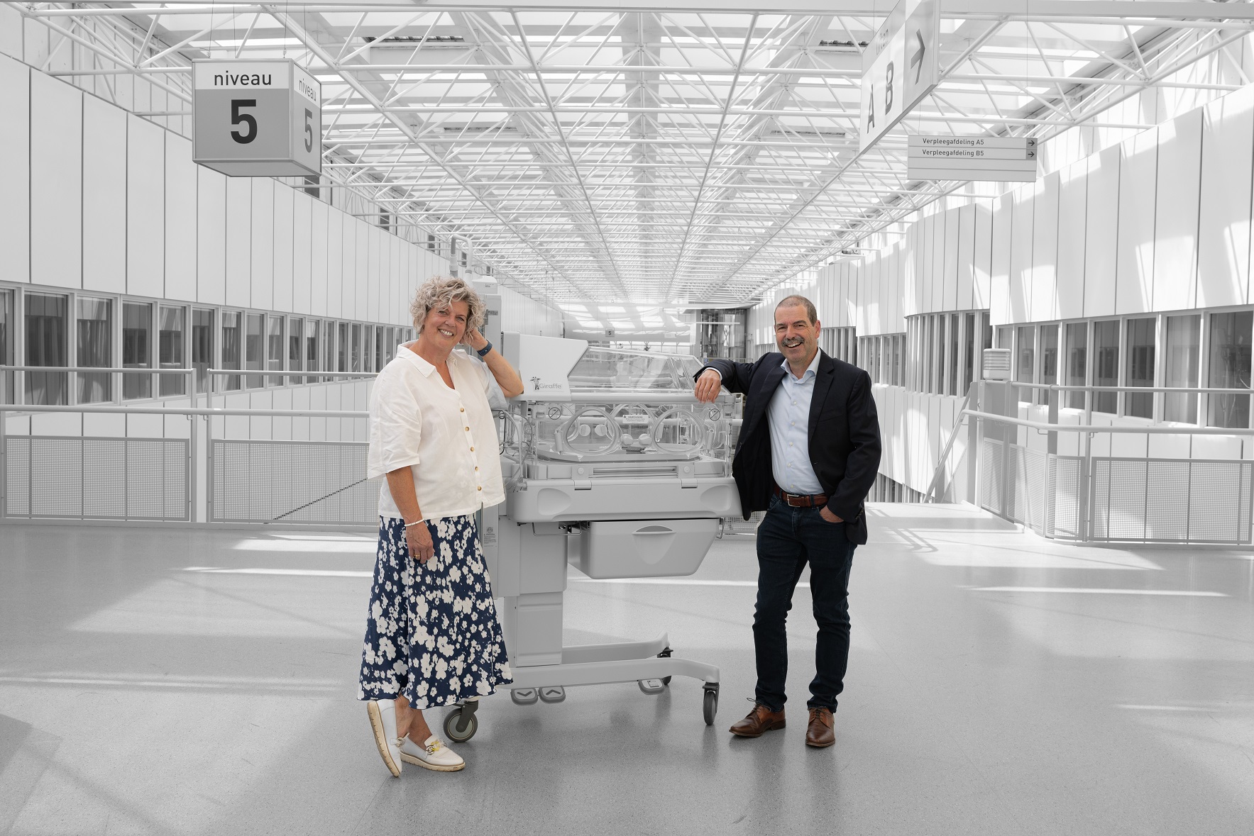 Edith Coonen en Jos Dreesen staan naast een couveuse tegen een zwartwit achtergrond