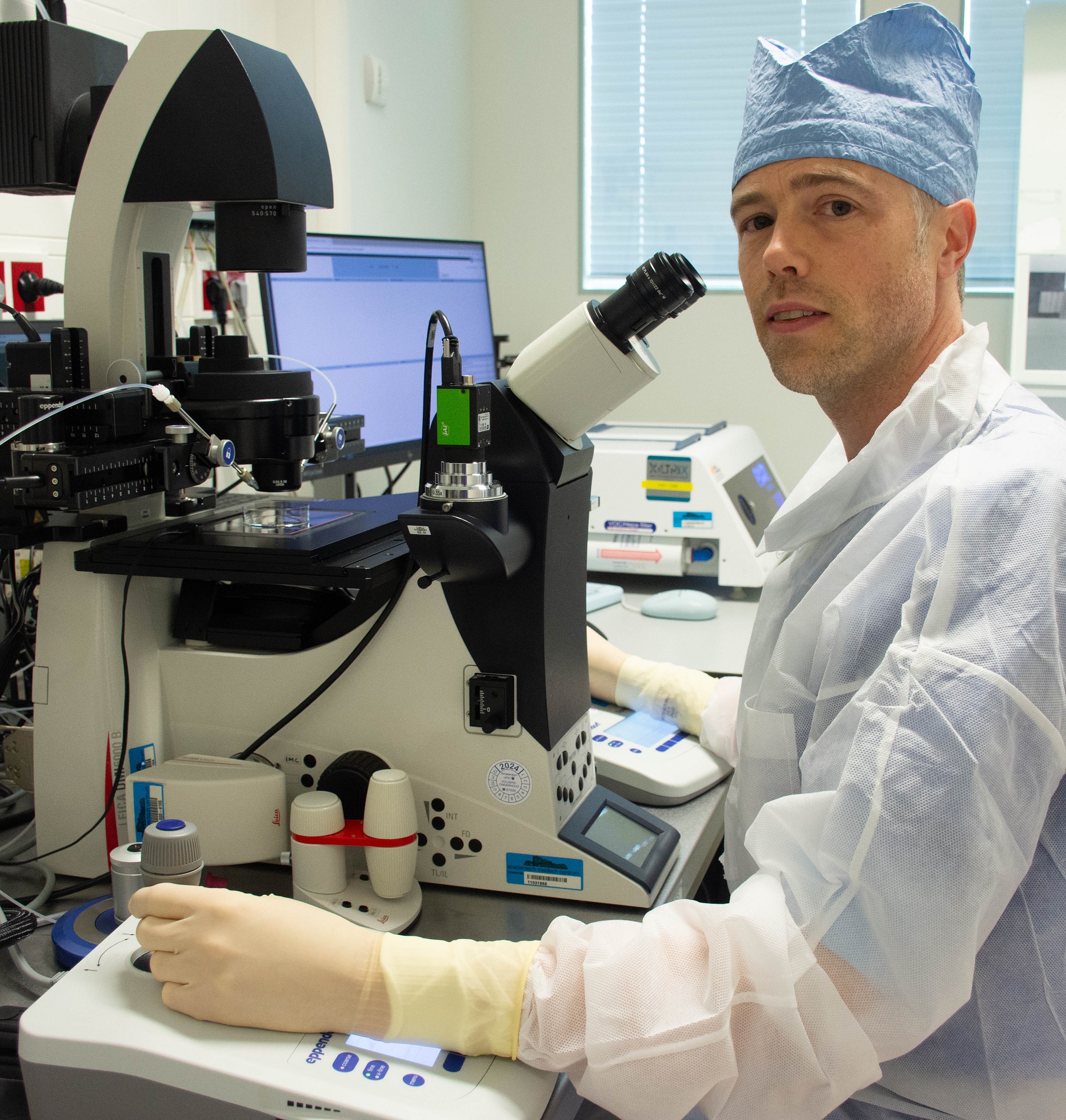 embryoloog zit achter microscoop en voert een biopsie uit