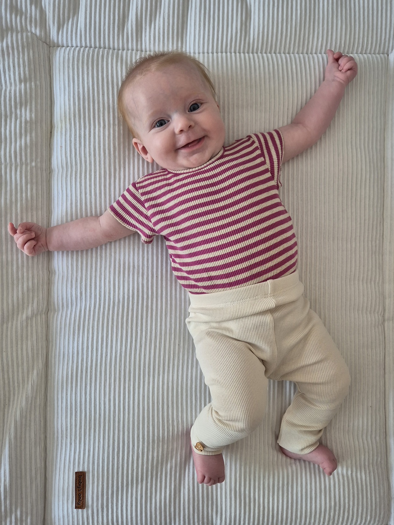 Baby in gestreept truitje op haar rug in de wieg