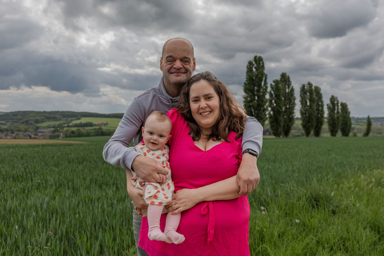Man en vrouw met hun baby dochter op de arm in een weiland