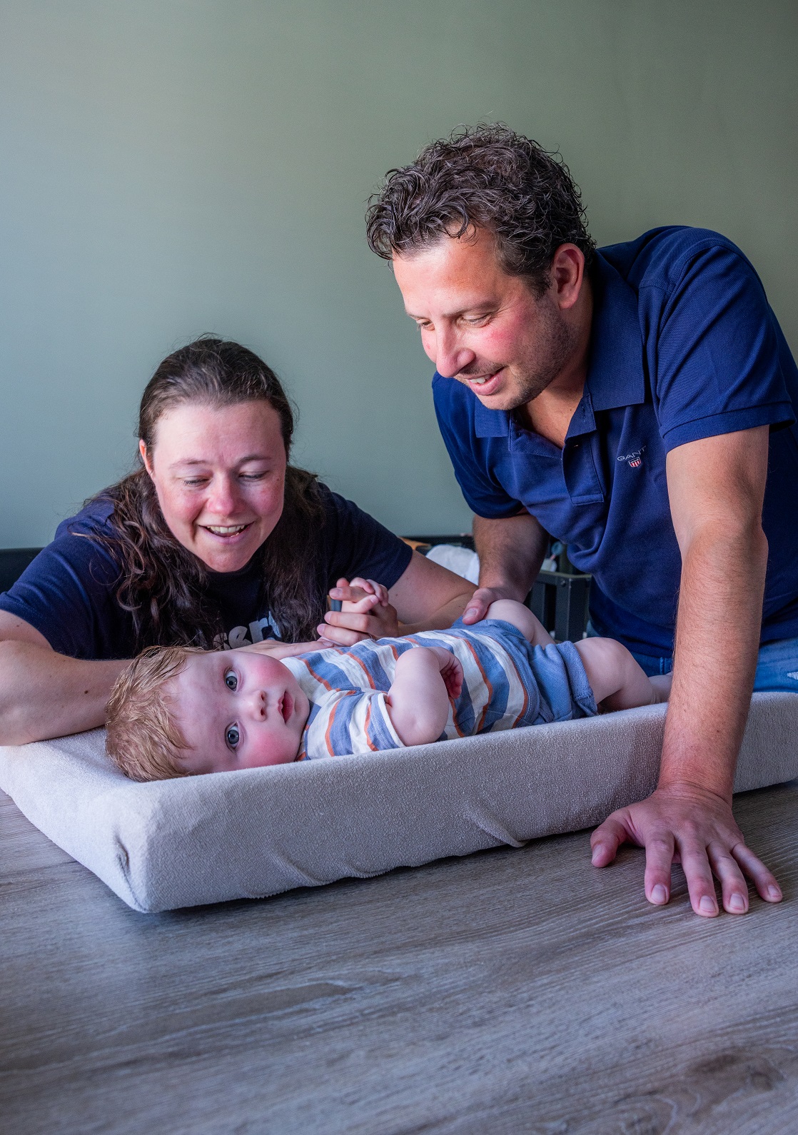 Man en vrouw kijken naar hun baby die op een aankleedkussen op tafel ligt