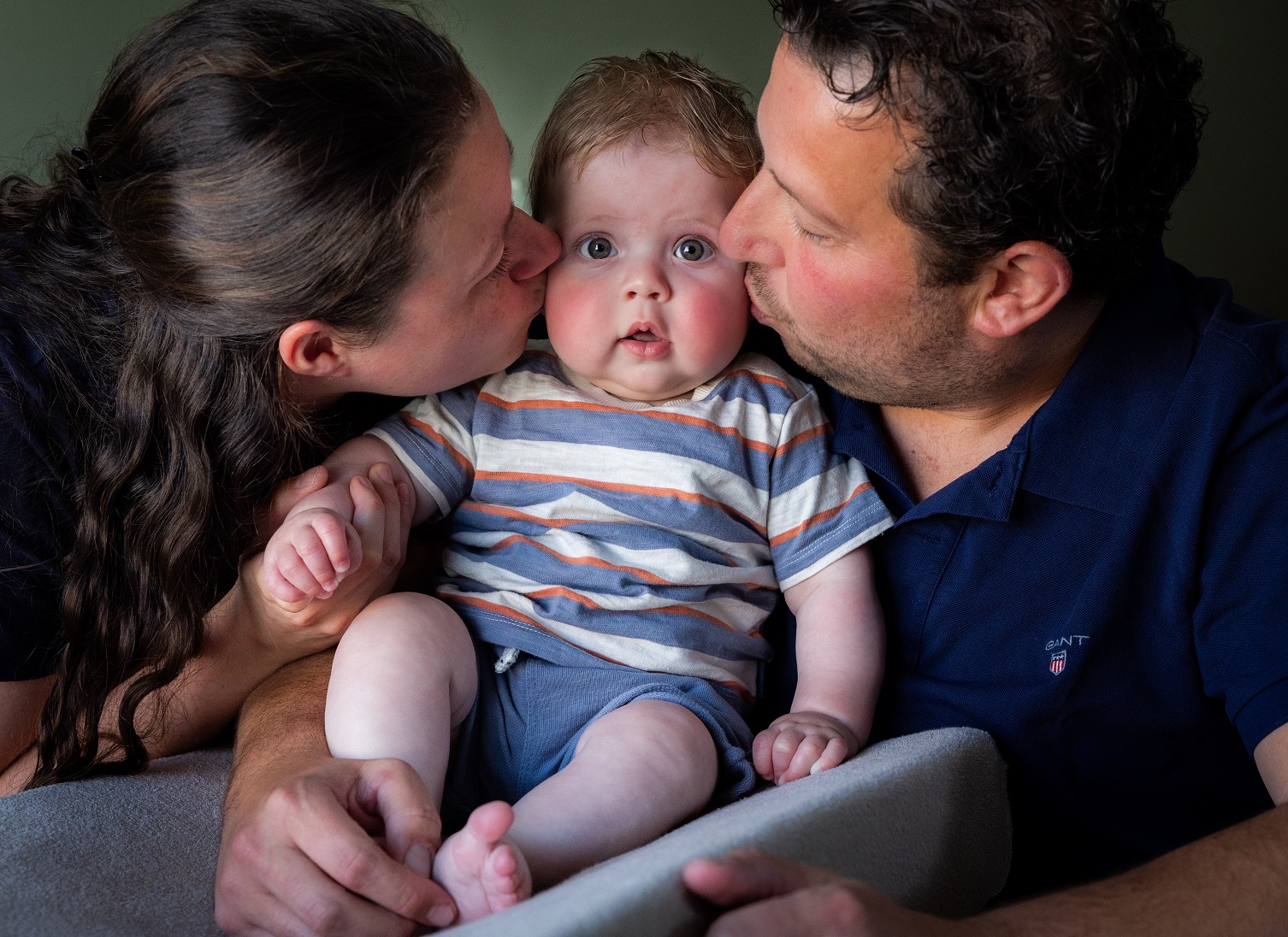 Man en vrouw kussen hun baby op de wang