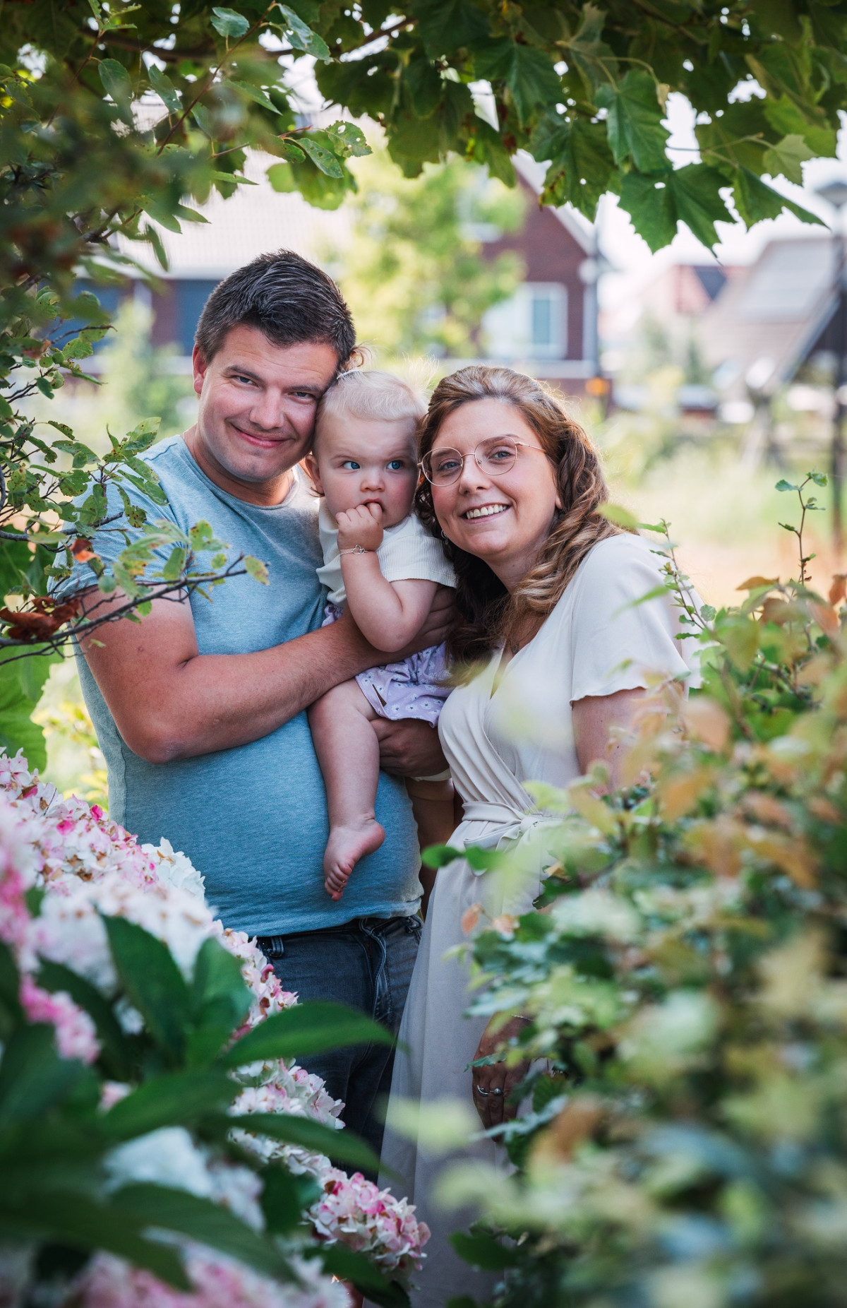 Man en vrouw met dochtertje op de armen in de tuin
