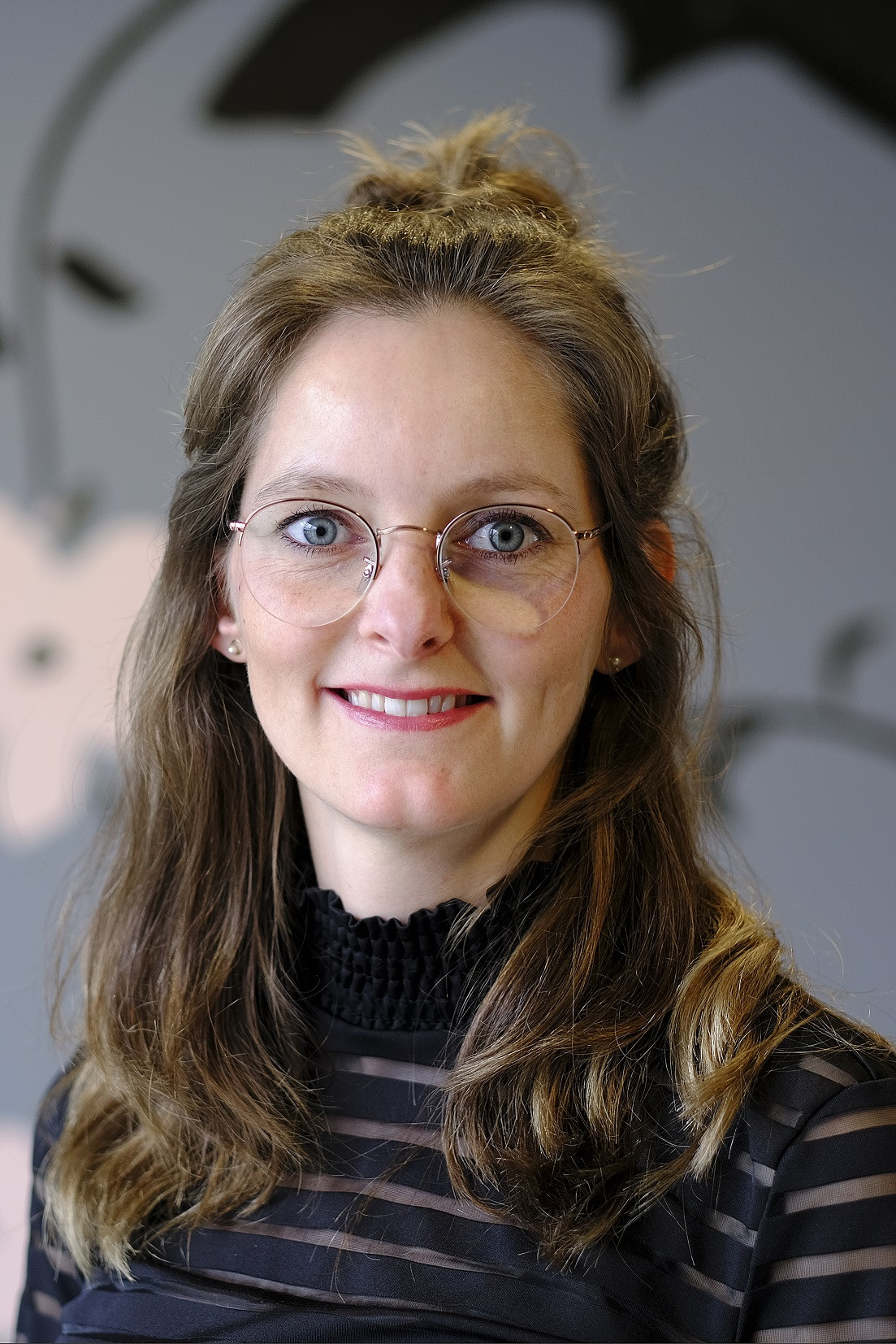 Portretfoto van Malou Heijligers tegen een bloemige achterwand