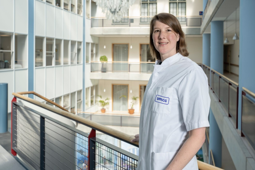 Dr. Nicole Corsten in dienstkleding staat aan balustrade in de hal van het UMC Groningen